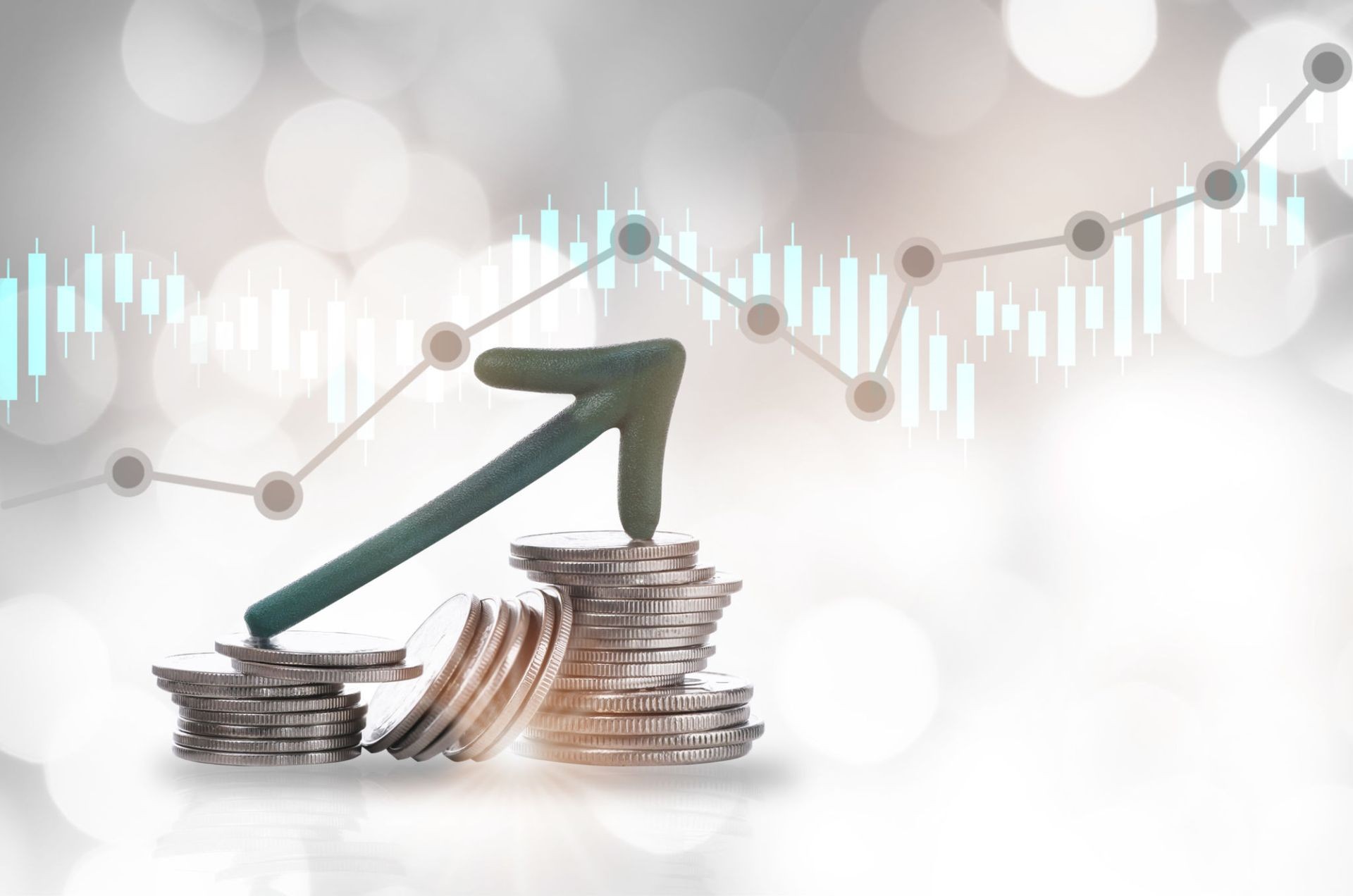 Stacks of coins with an upward arrow against a background of financial graphs and charts.